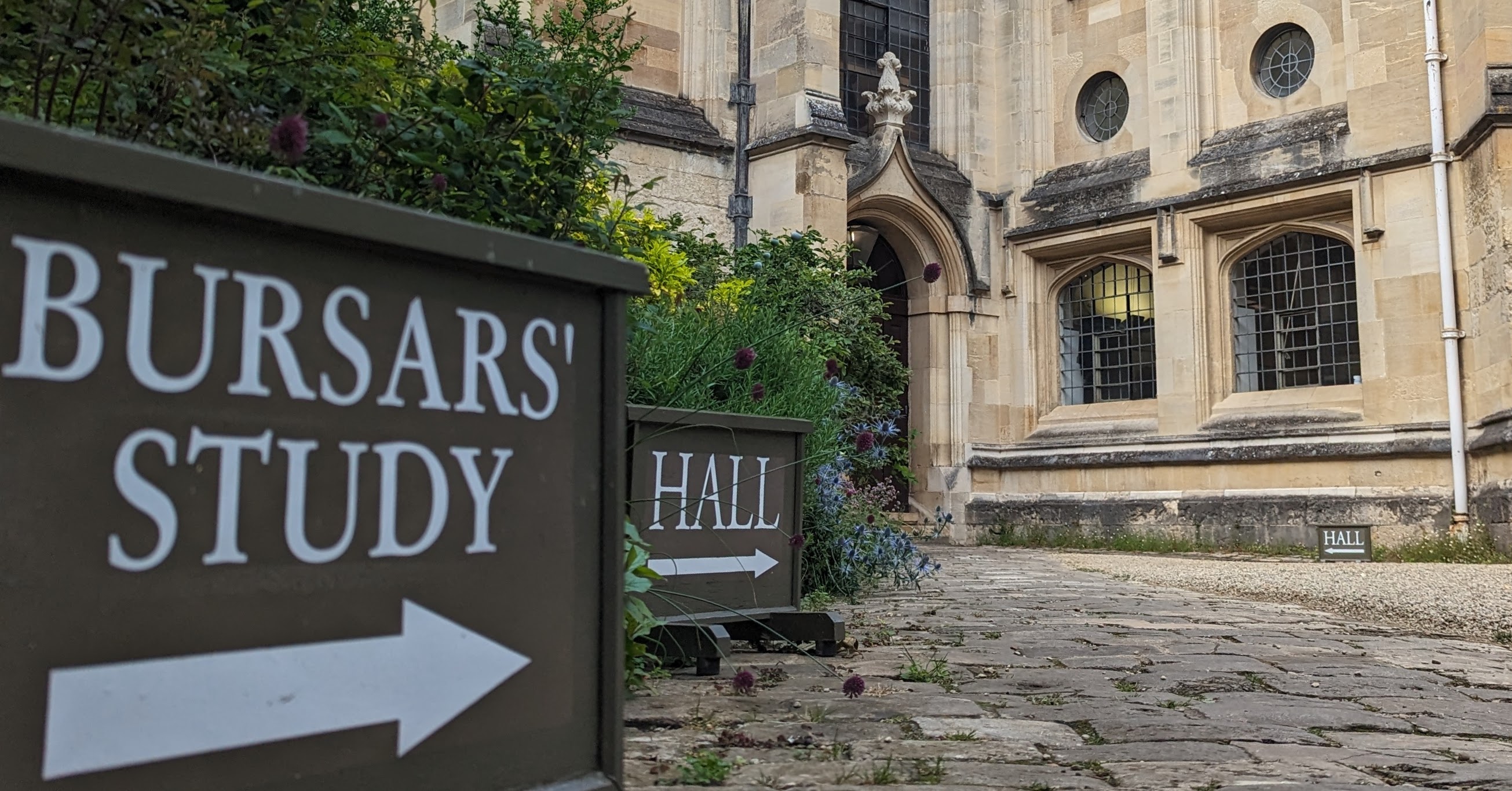 A sign saying Bursars study with an arrow pointing right.  In the background another sign saying Hall and part of the College buildings