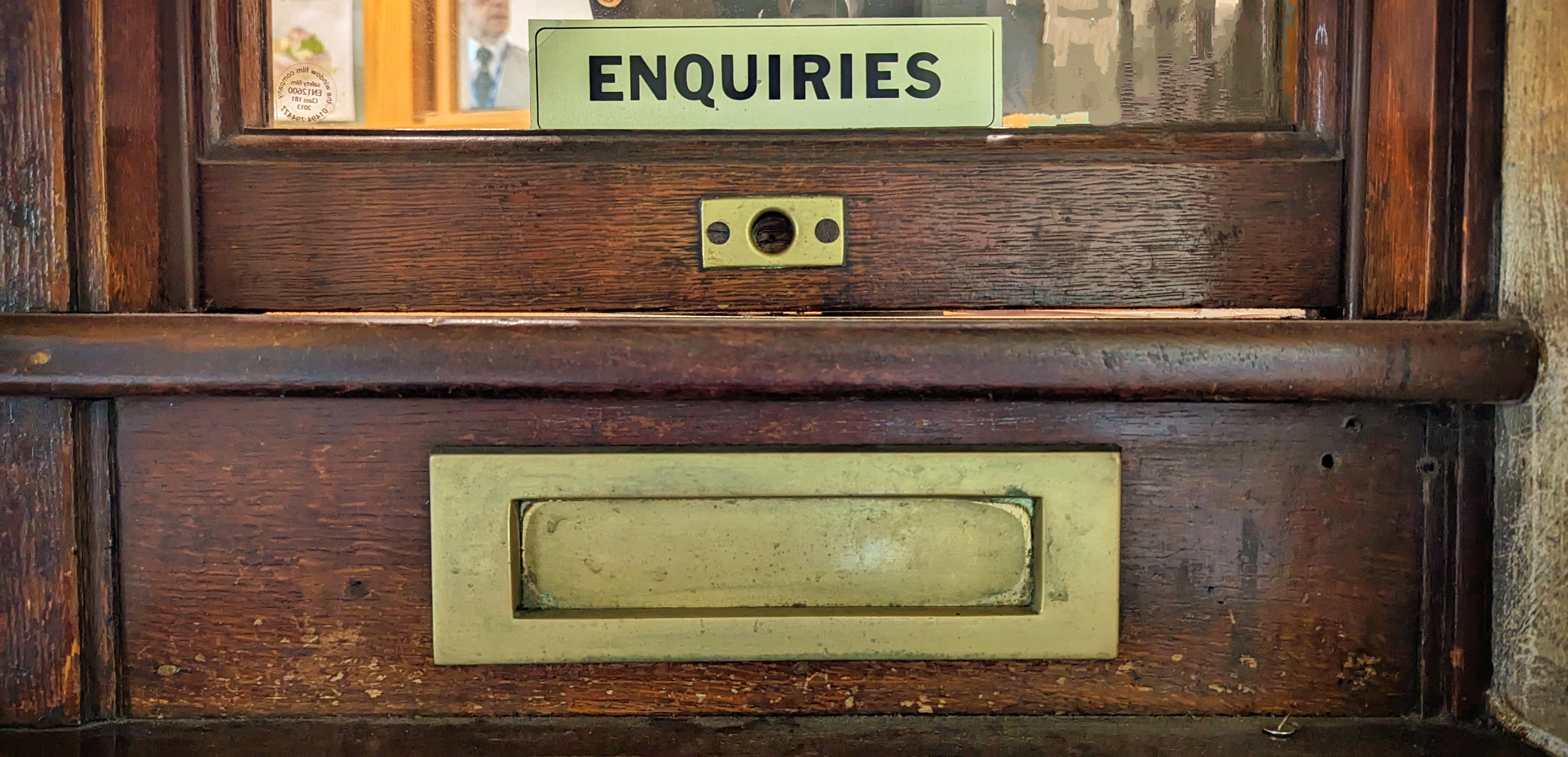 A picture of a brass letter box set in dark wood.