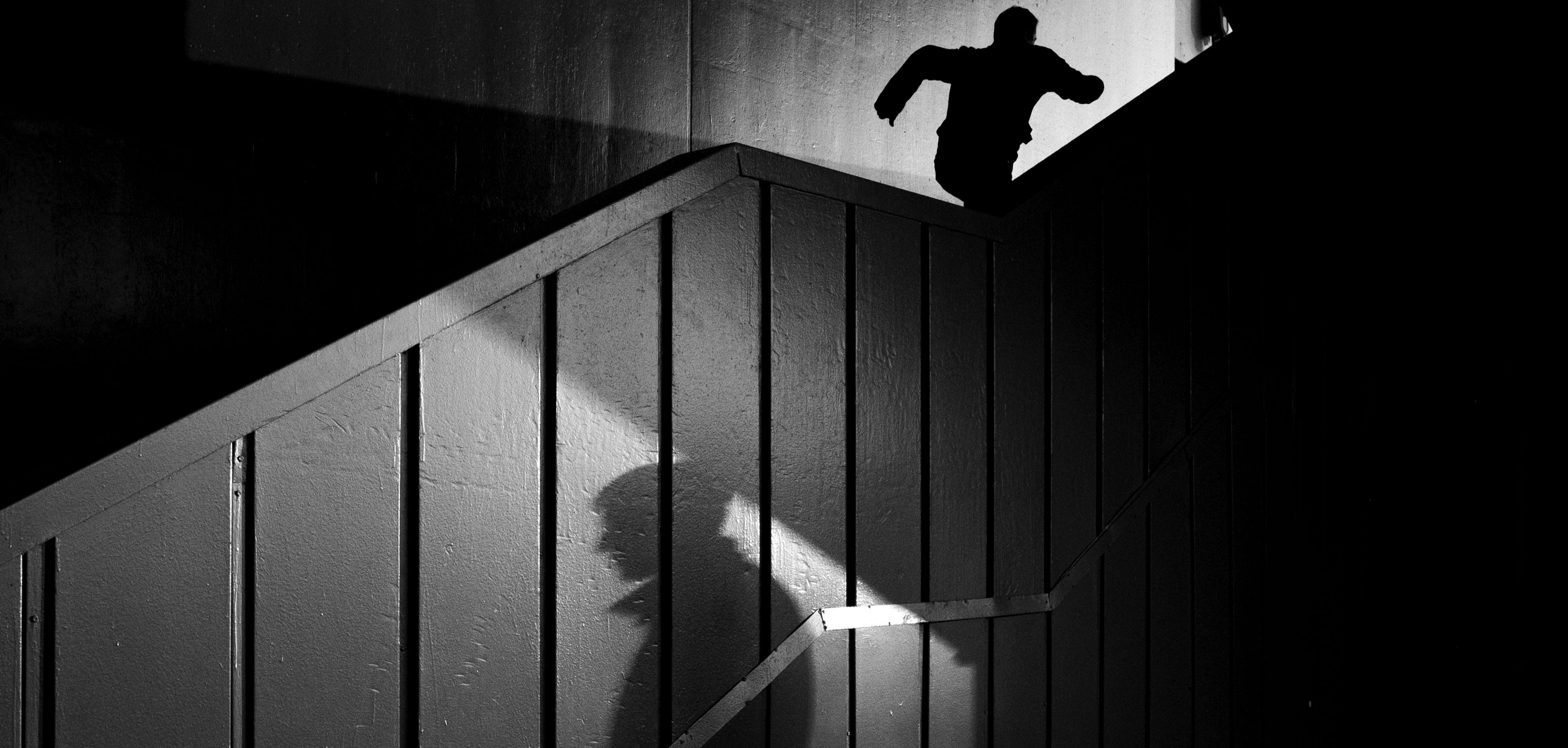 Two shadowy figures in black and white, one standing and one running