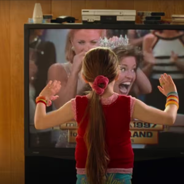 A still from the movie Little Miss Sunshine. A young girl faces a television on which a beauty pageant is being shown.