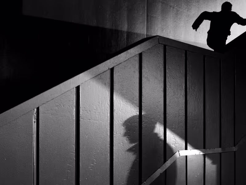 Two shadowy figures in black and white, one standing and one running